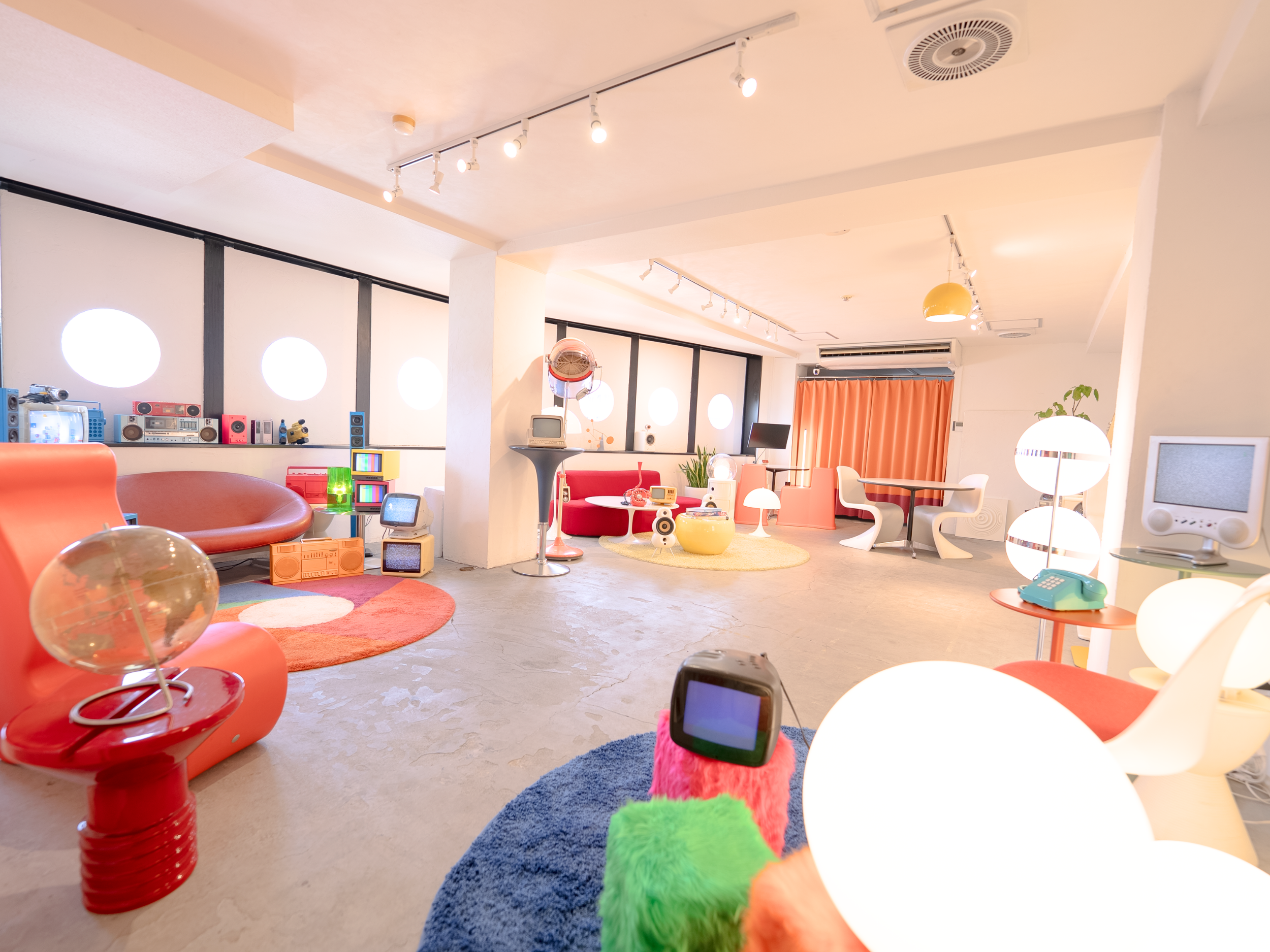 レトロポップ平和島の入り口側から見た全景写真。丸窓や曲線家具、カラフルなラグ、ブラウン管テレビが見えるスタジオ全体の様子