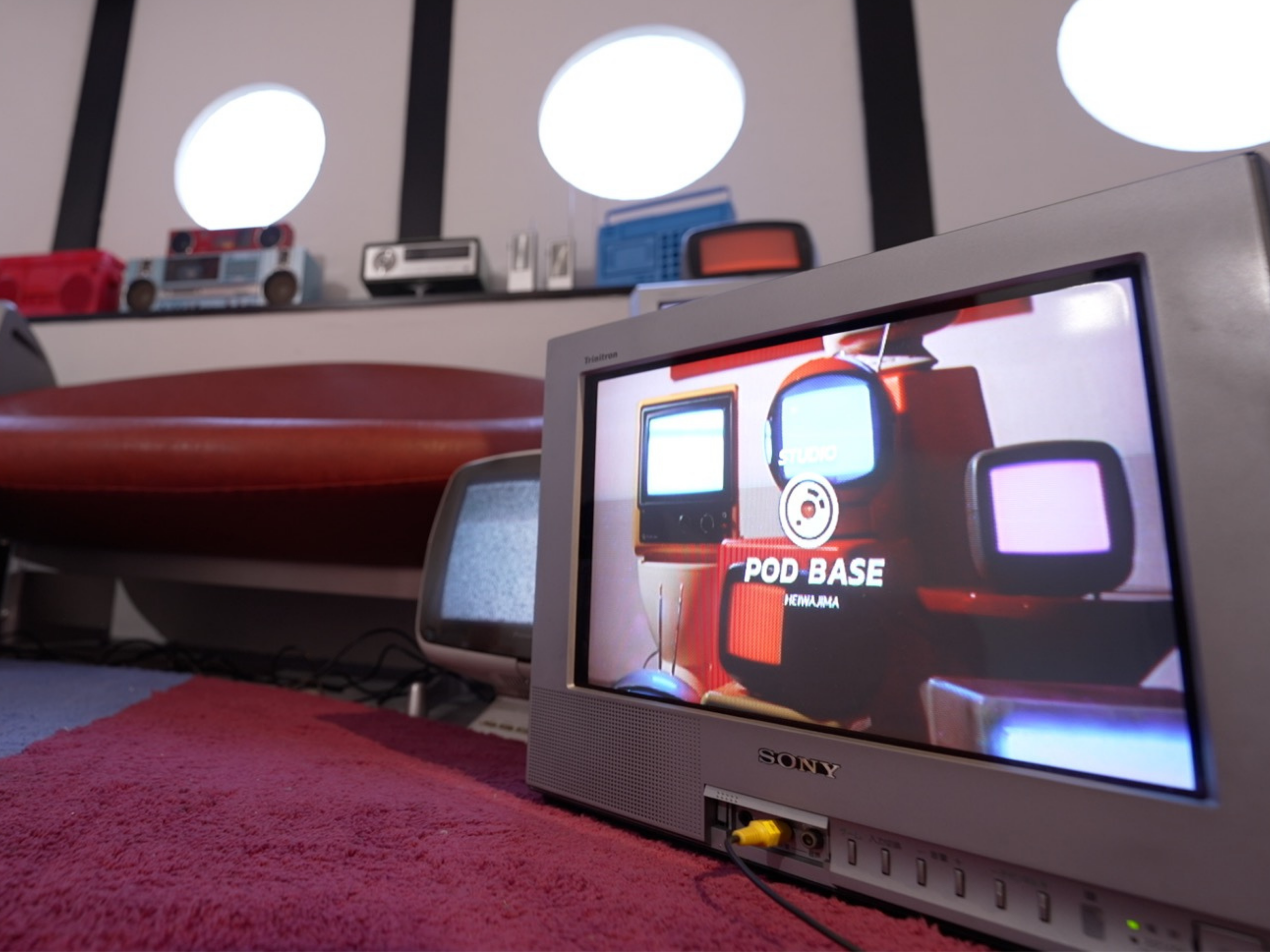 ブラウン管テレビと丸窓、ソファが並ぶレトロポップ平和島の一角