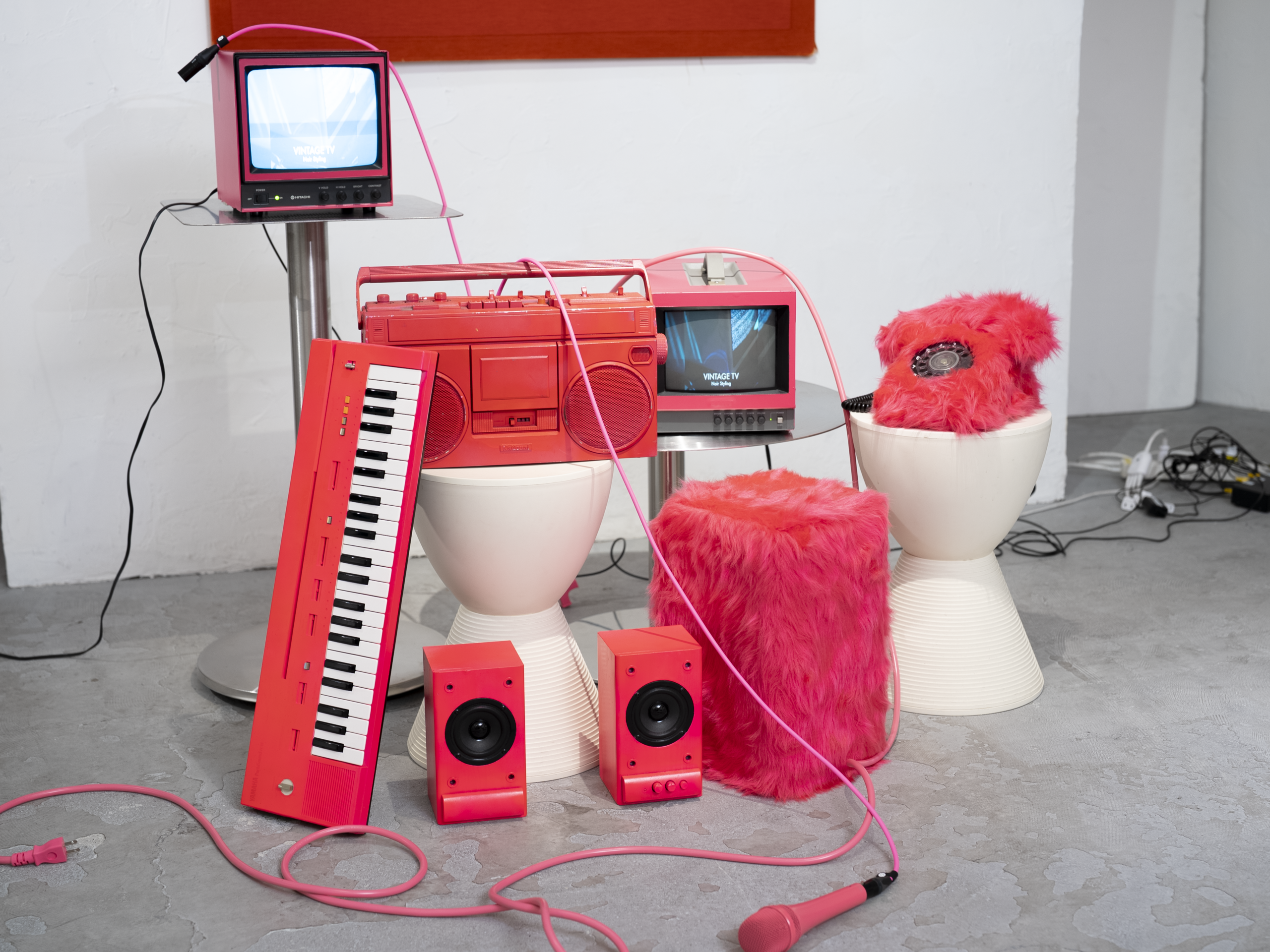 ピンクのキーボードやマイク、スピーカー、ラジカセ、ブラウン管テレビを組み合わせたレトロポップ平和島のセット写真。ピンクを基調にまとめた一角